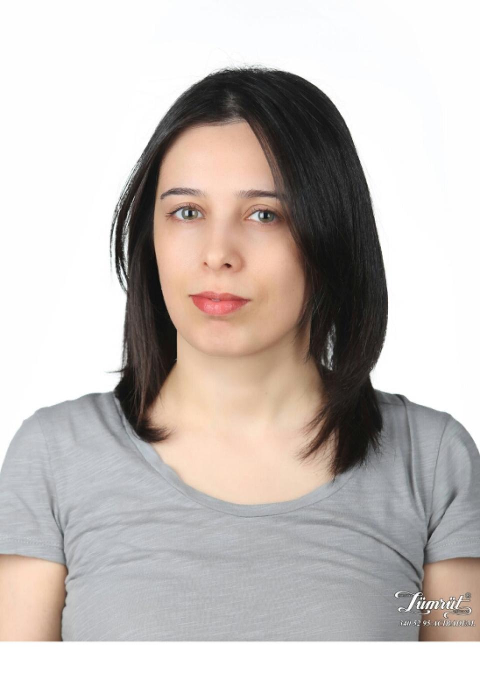 A photo of Dr. Ebru Eren, a white woman with mid length dark hair and wearing a grey shirt.
