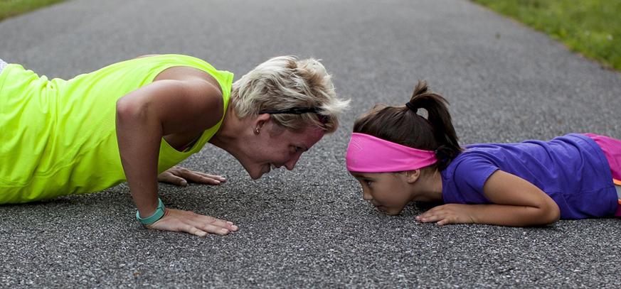 Smiling middle aged woman and a girl doing push-ups