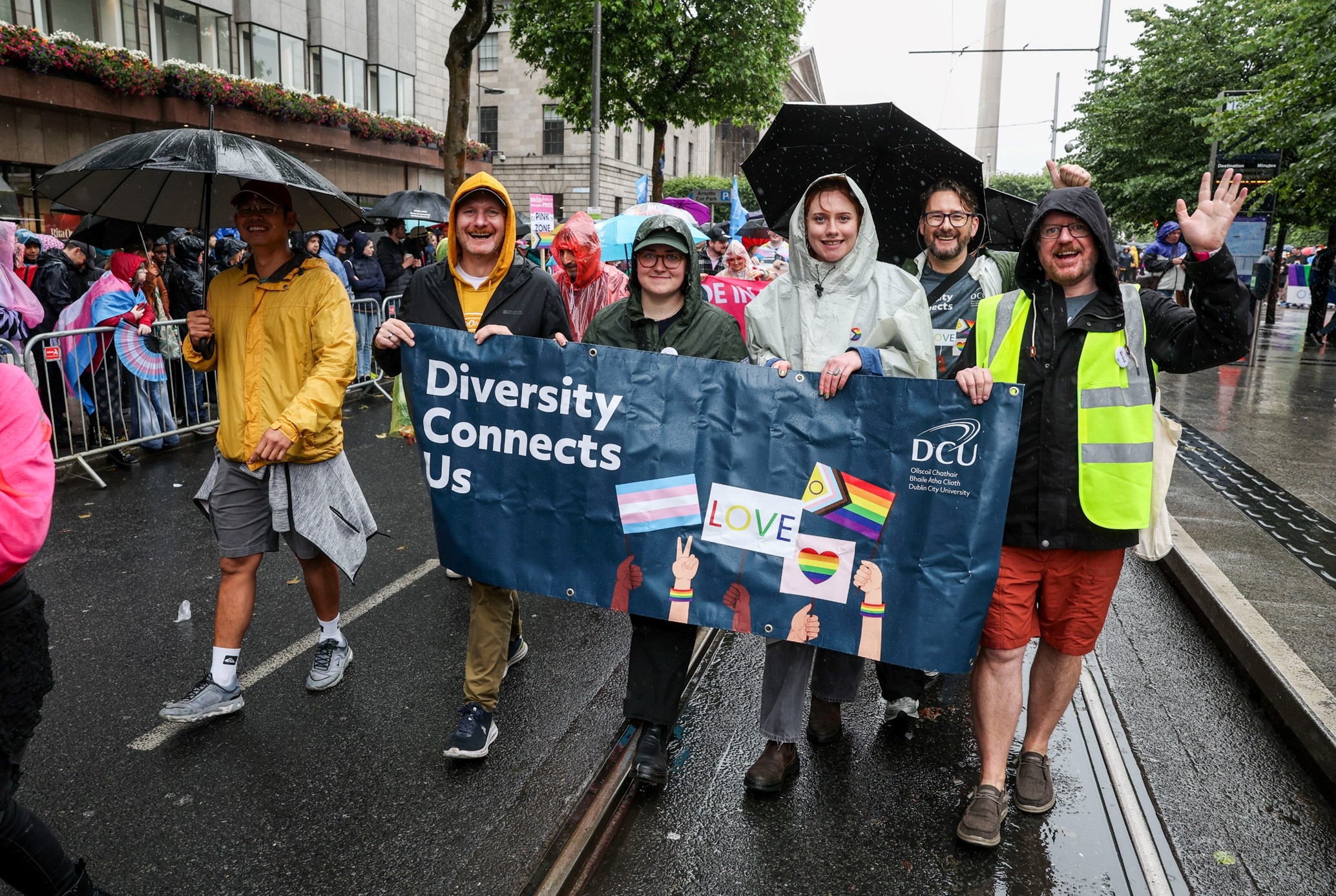 Members of the Pride+ staff network holding a DCU Diversity Connects Us banner in the Dublin Pride parade 2024.