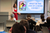 A woman speaking to a class of primary school age children