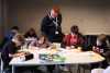 a man looks at the work of children seated around a table