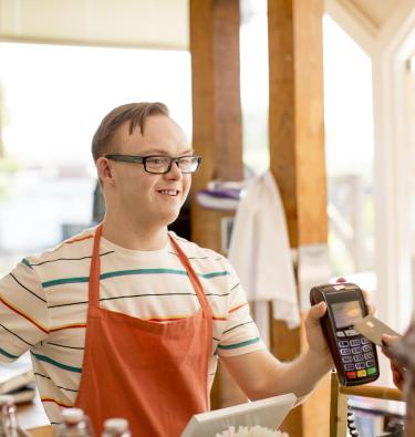 young person with a disability working in a cafe