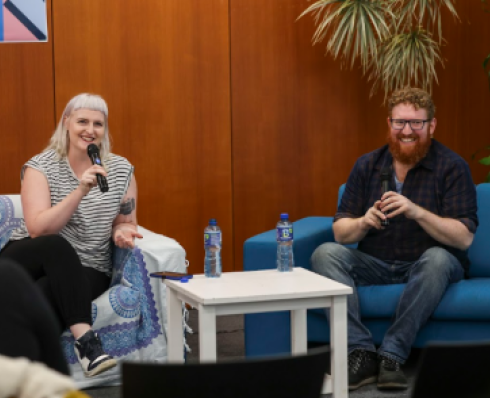 Writers Sophie White and Dave Rudden sit on couches holding microphones 