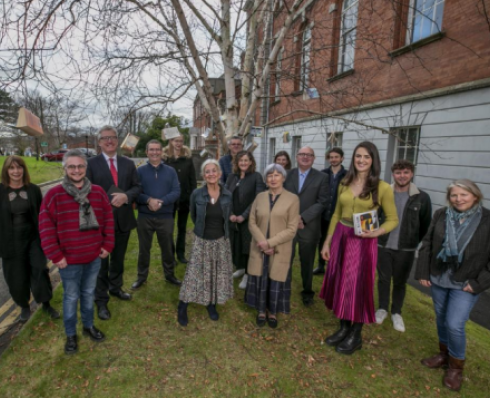 a group of people standing beside a building with books in their hands