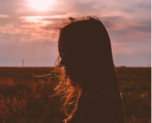 A picture of a woman with her hair blowing over her face