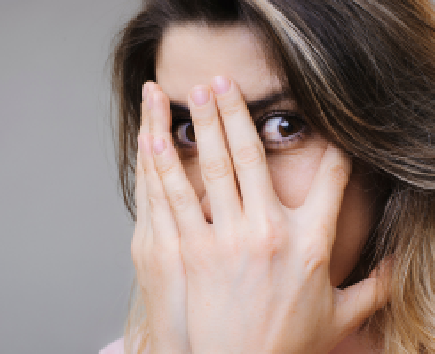 A woman hiding behind her hands