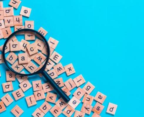 Magnifying glass over wooden squares with letters