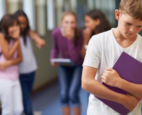 Student holding a copy book with some other students laughing behind them