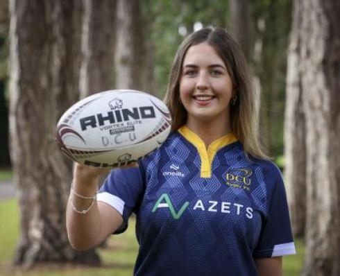 Female rugby player posing with a rugby ball