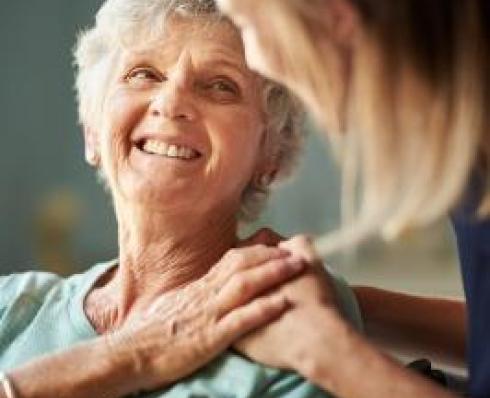 Shows elderly woman and carer