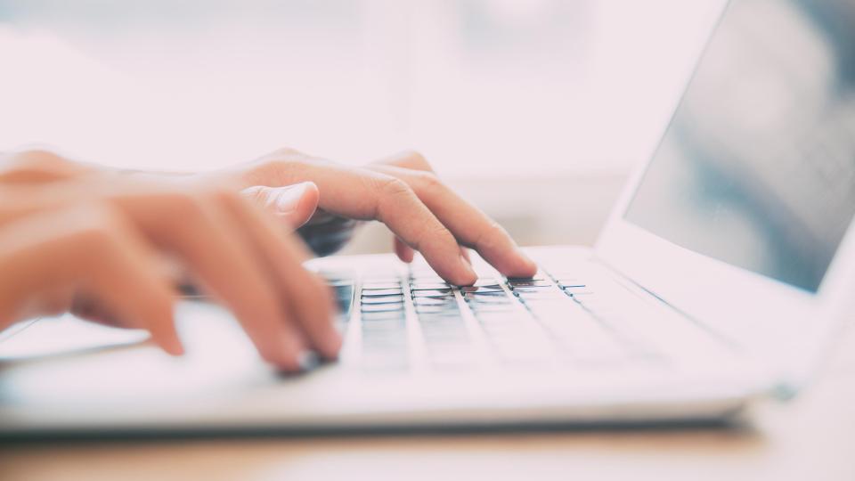 Two hands typing on a laptop