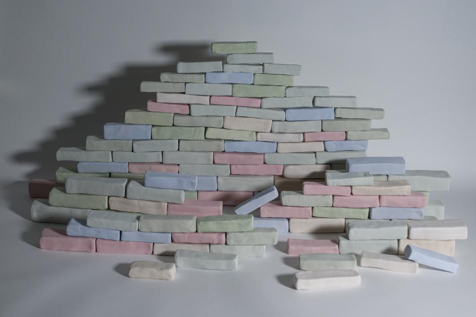 Pink, Green and Blue bricks made from clay stacked side by side and on top of eachother