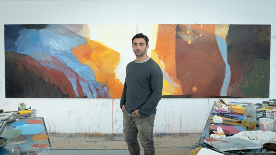 Artist Richard Hearns stands in front of his work in his artist studio