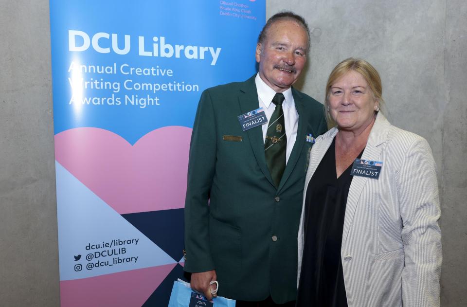 A man and a woman standing in front of a DCU Library banner