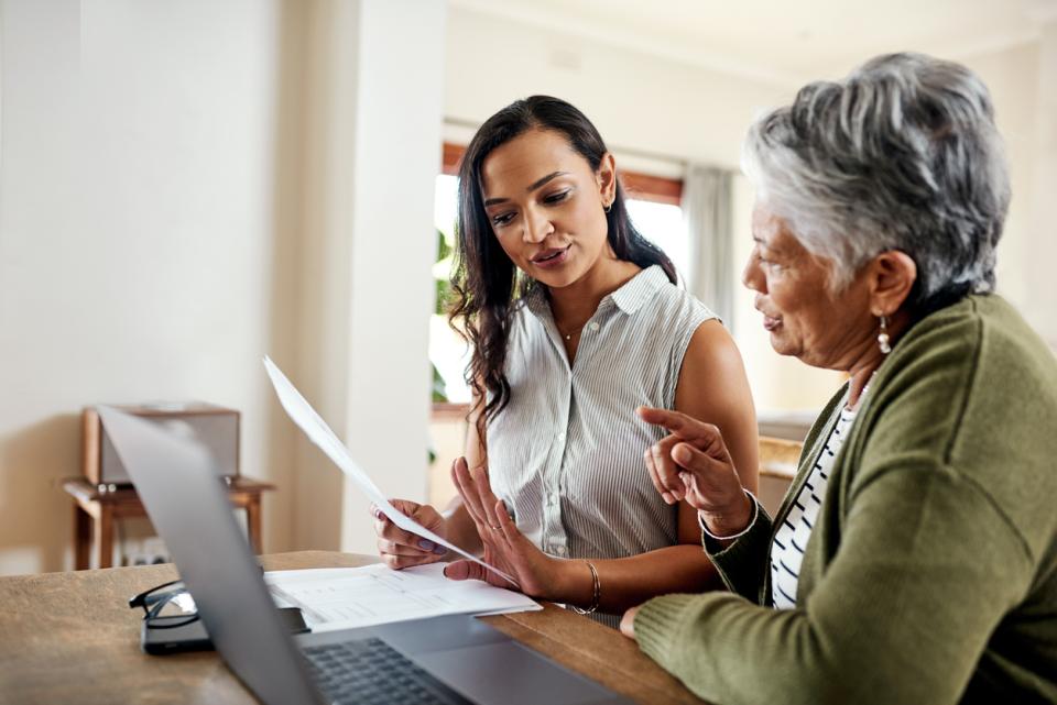 Two women looking at paperwork and laptop