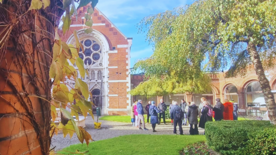 People gathering in courtyard in front of red brick chapel