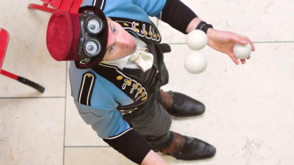 Juggler wearing red hat and blue jacket