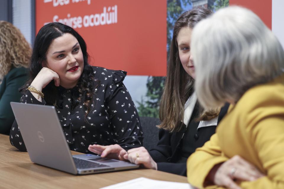 Three female colleagues in discussion in front of a laptop