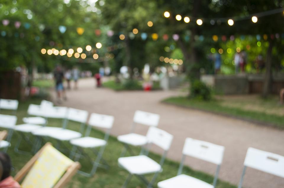 A row of white garden chairs laid out in a garden.