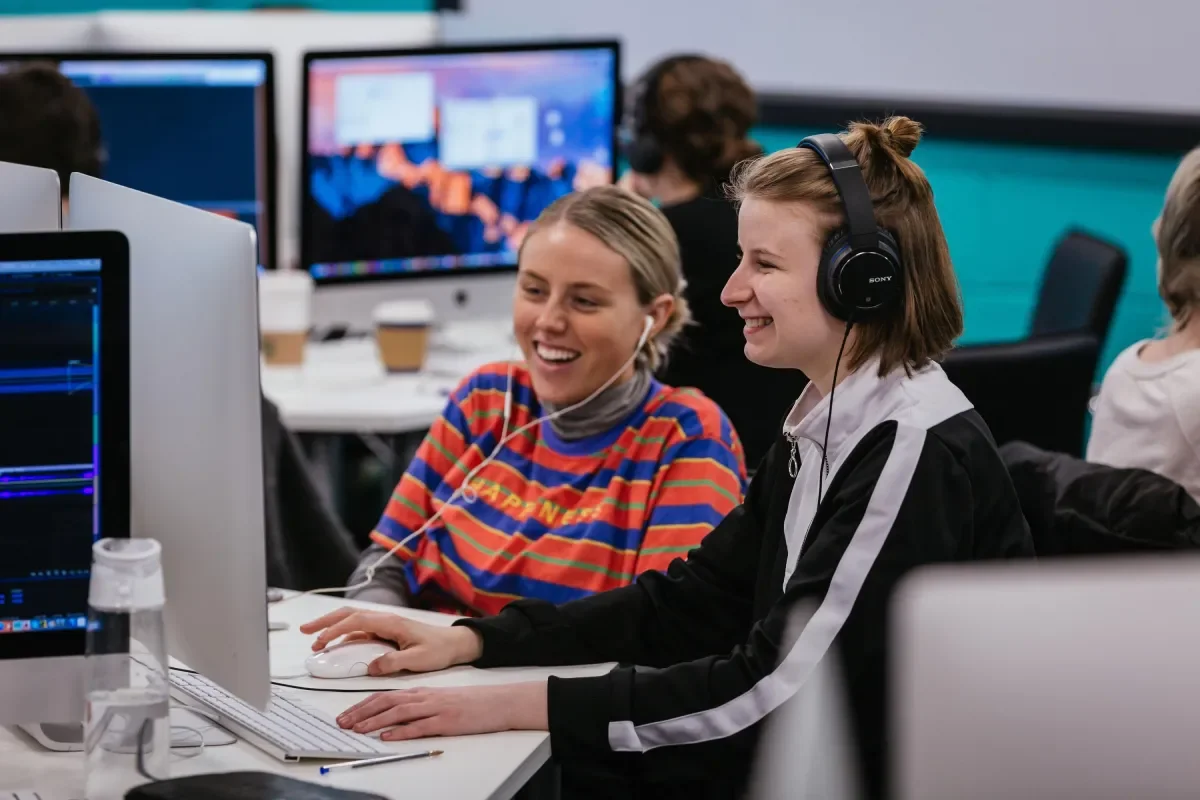 two students laughing while looking at a PC