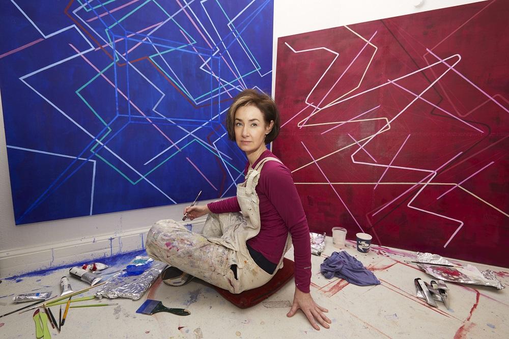 Elva Mulchrone in front of two of her paintings