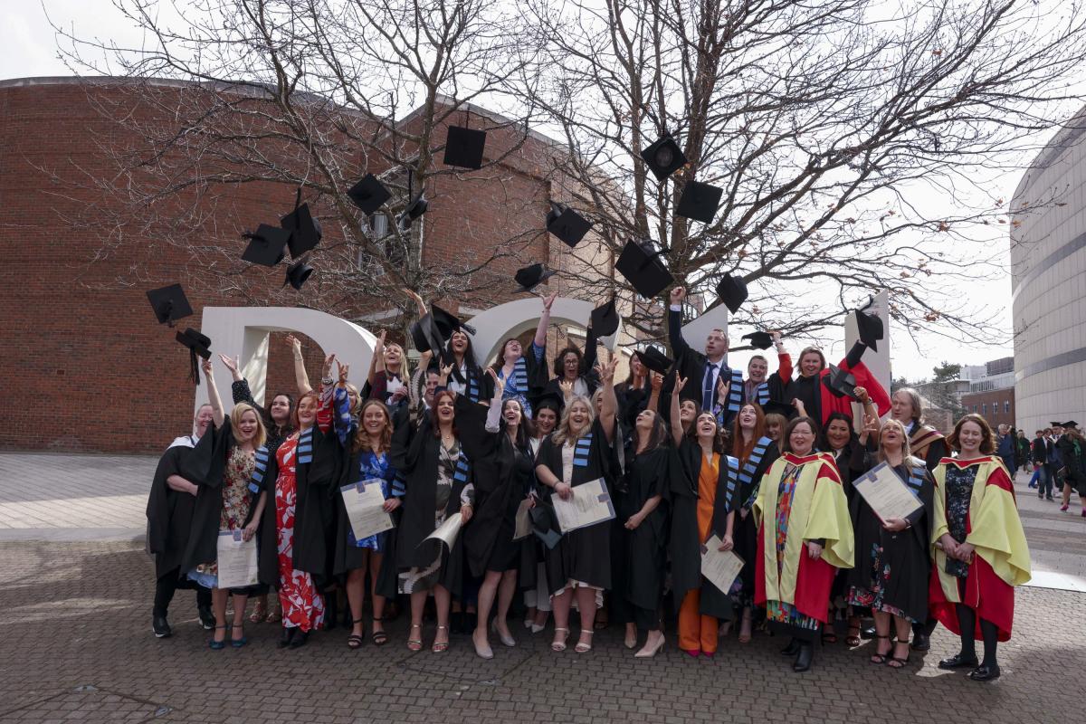 A group picture of the first graduates from the SPHE/RSE Graduate Diploma throwing their caps in the air.