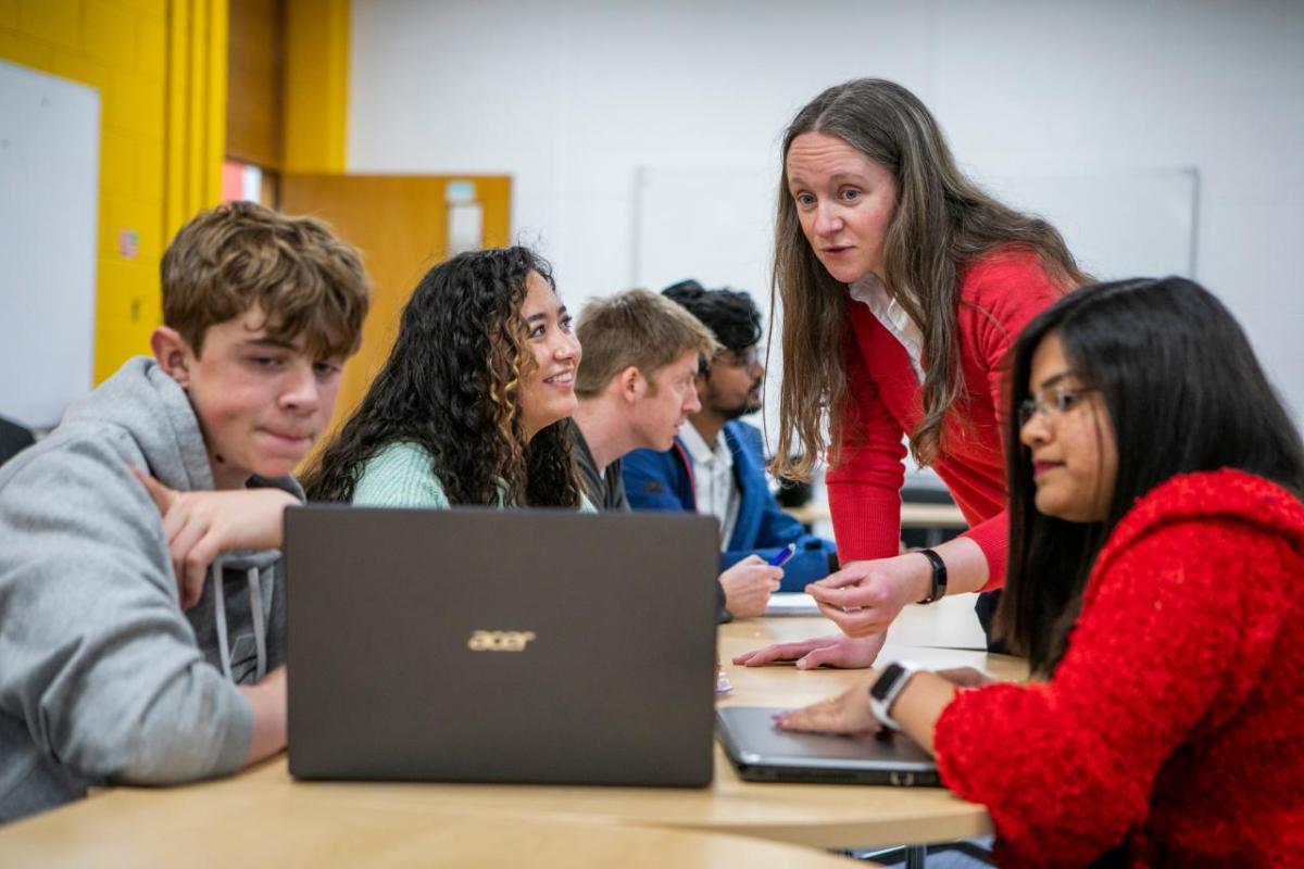 Students at a desk collaborating on a laptop