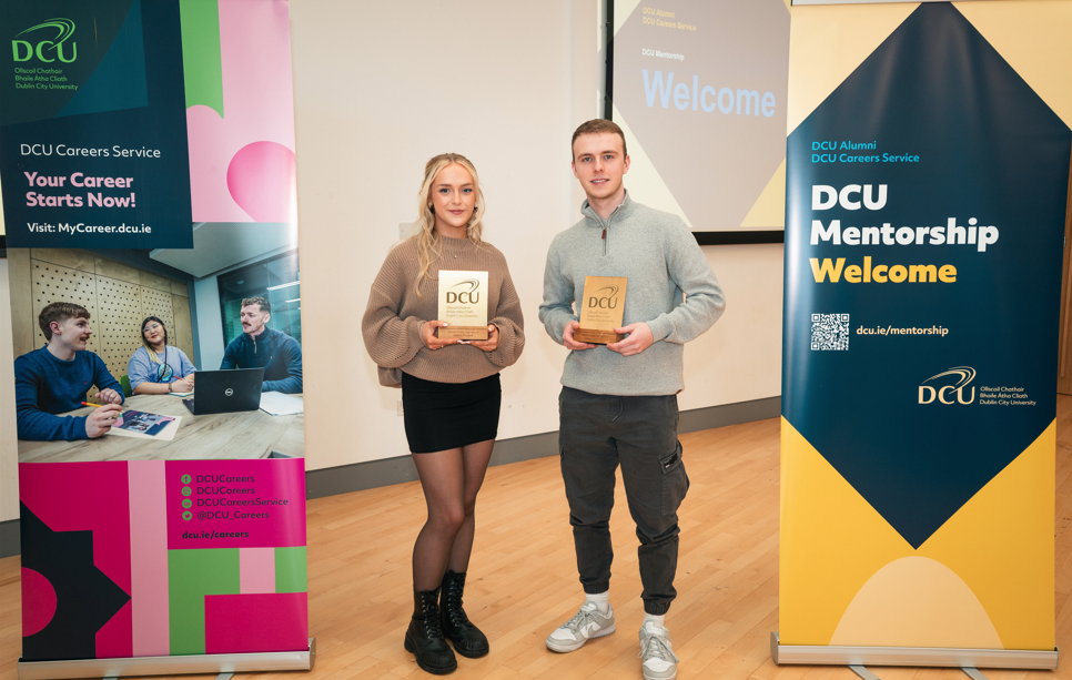 Two students holding Mentorship of the Year trophies. 