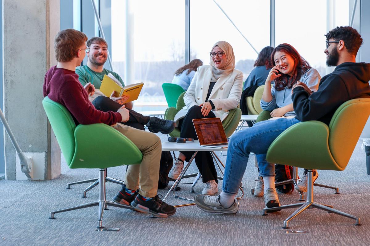 Group of 5 students round a small table 