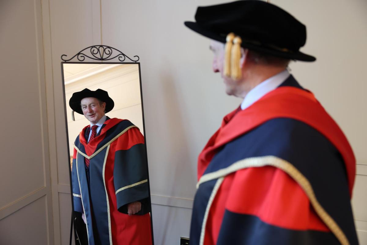 Enda Kenny looks at himself in the mirror, wearing his honorary robes.