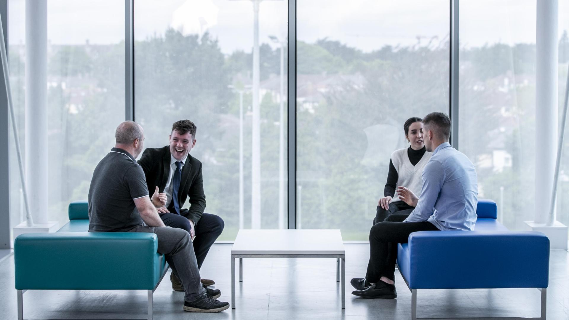 Four people in conversation in open plan office