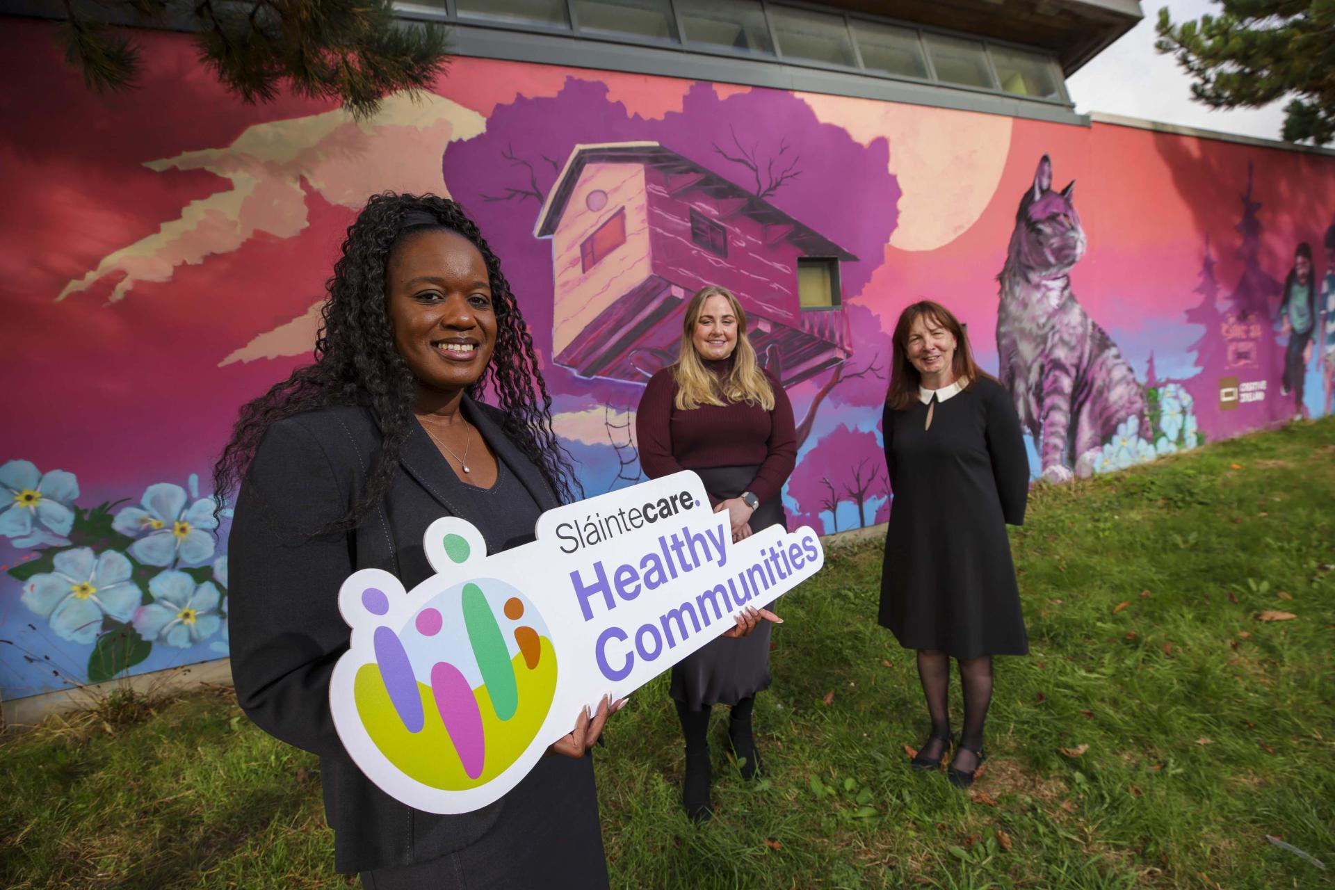 Three people at the launch, holding a Sláintecare Healthy Communities sign