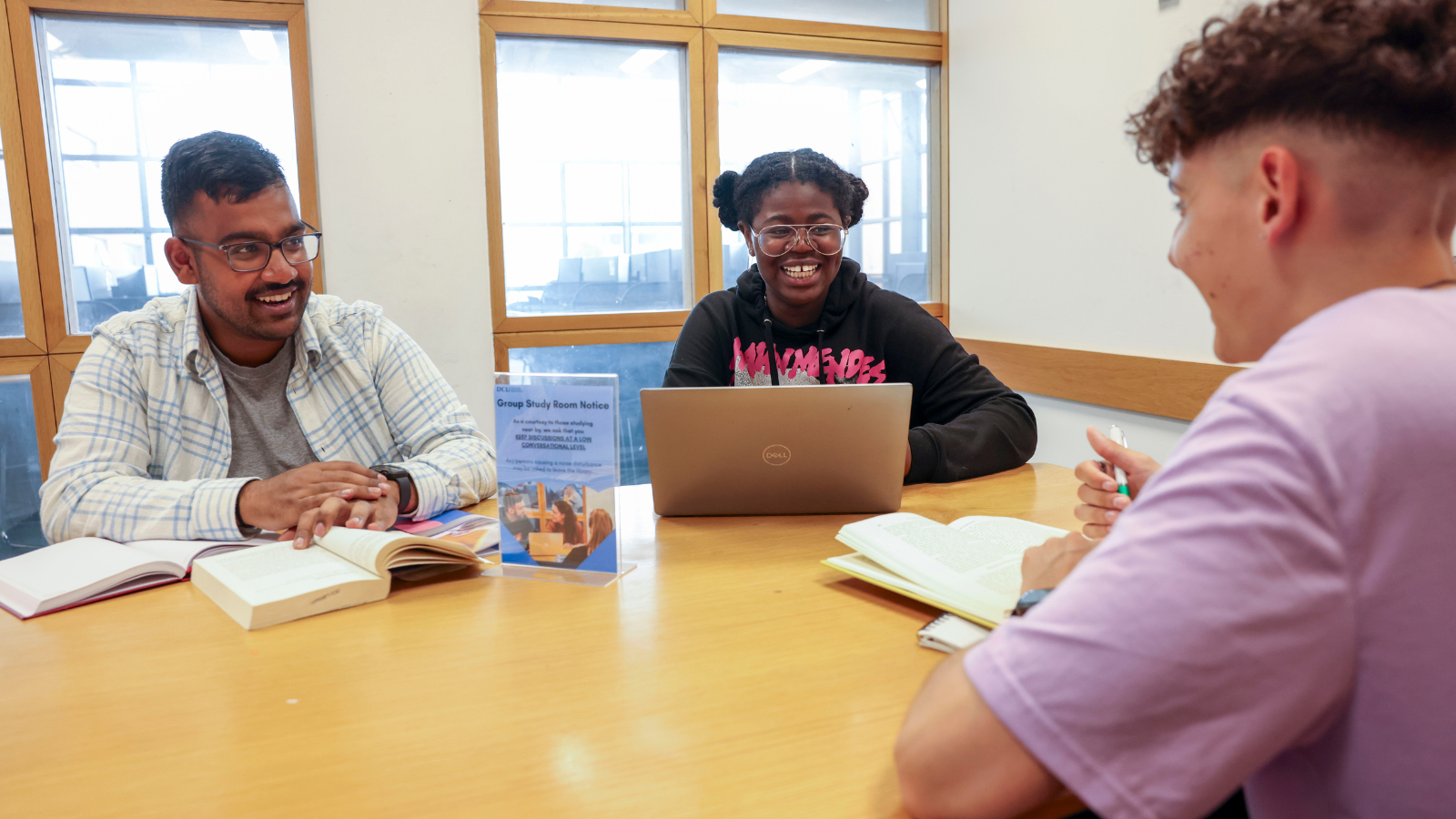 3 stduents studying with laptops and notes in a group study rom in O'Reilly library