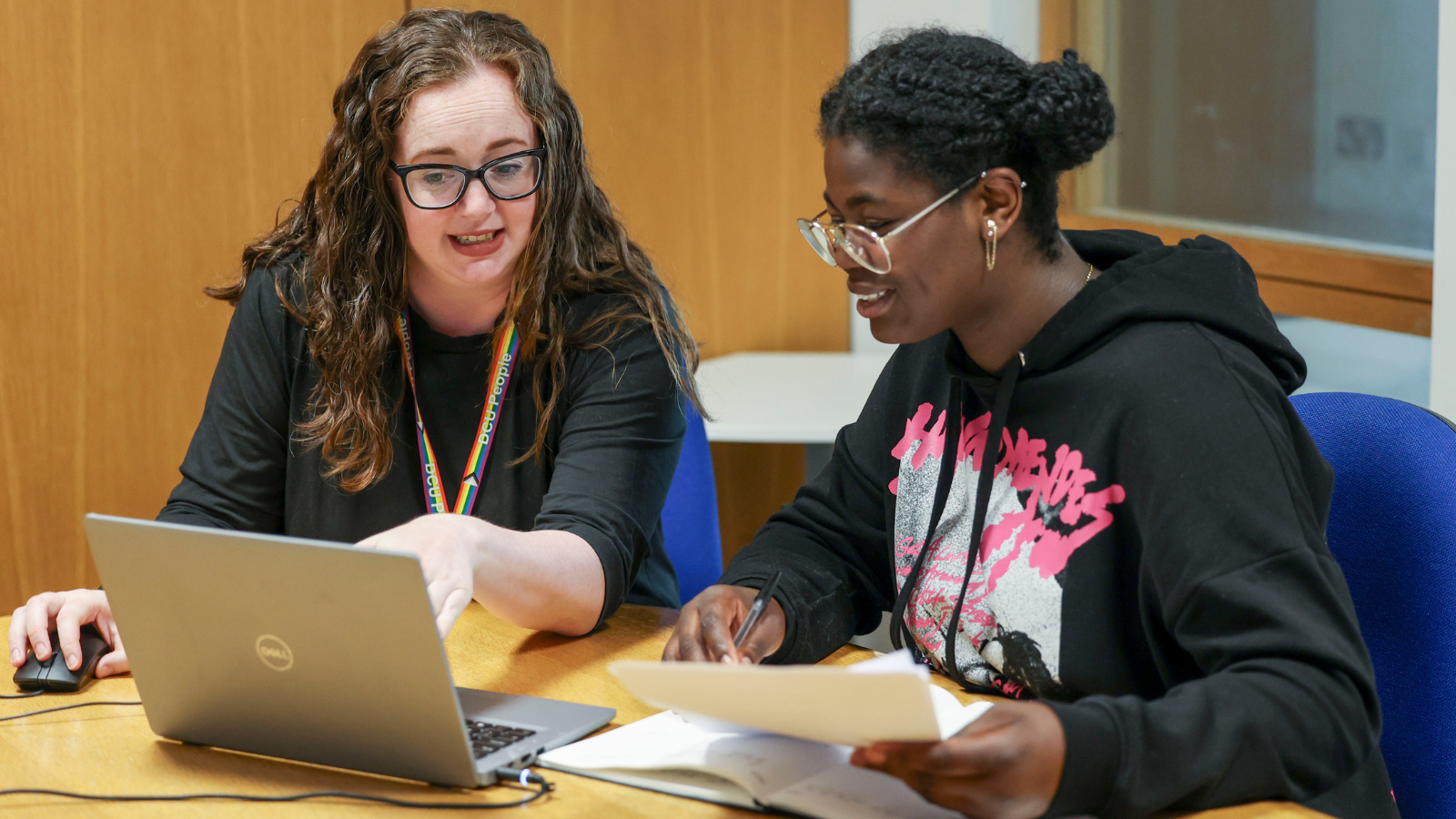 Two people sitting at a desk looking at laptops