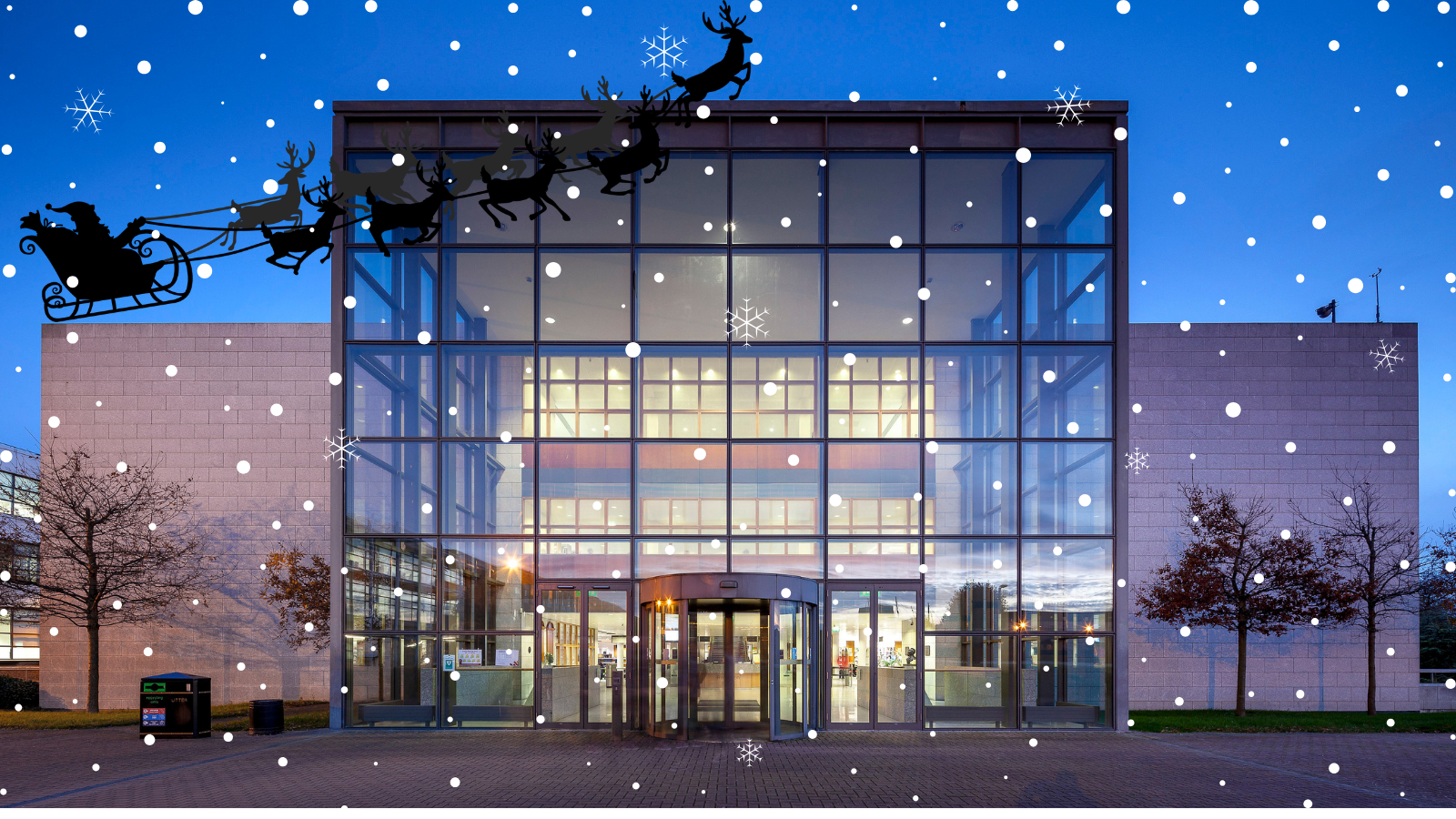 O'Reilly library at night with an overlay of snow and a sihouette of Santa and his reindeer in the sky